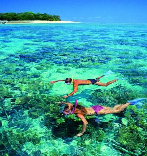 two people swimming in the clear blue ocean