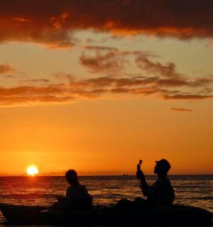 two people sitting on a boat watching the sunset
