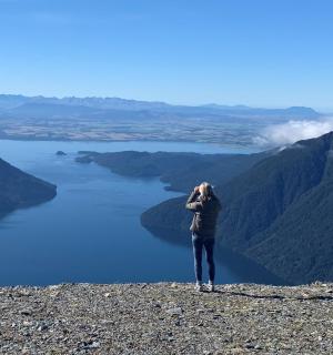 一位女士站在山顶俯瞰湖泊
