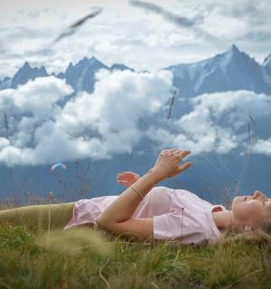 一名女子躺在田野里,双手高举