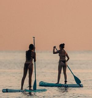 zwei Frauen in Badeanzügen auf Paddle-Boards im Wasser
