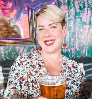 一位女士坐在桌边，手里拿着一杯啤酒