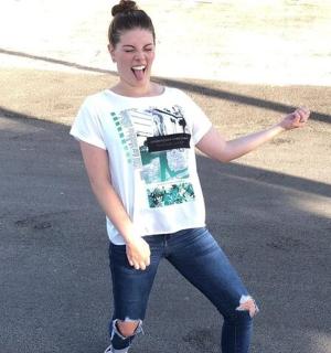 一位身穿白衬衫和牛仔裤的女士站在街上