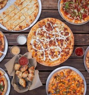 stůl prostřený různými druhy pizzy