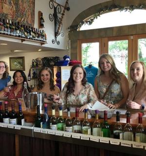 a group of women standing behind a bar with wine bottles