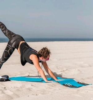 a woman doing a handstand on a surfboard on the beach