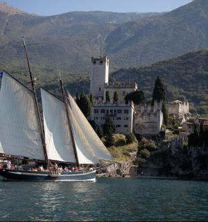 a sail boat in the water in front of a castle