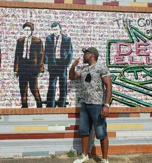 a man standing in front of a wall with a mural