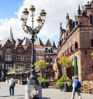 a group of people walking around a city with a street light