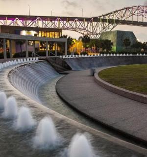 a water fountain in front of a building with a bridge