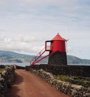 a red lighthouse on the side of a dirt road