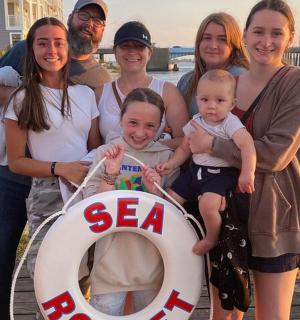 一群人站在码头上，手里拿着一块牌子