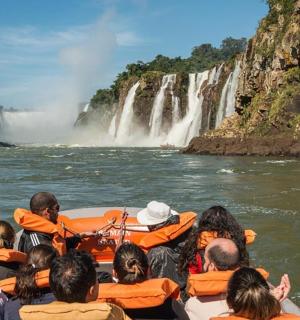 a group of people in a raft in the water at a waterfall