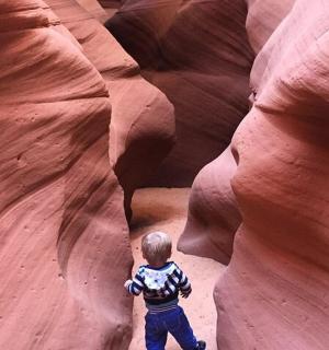 a young boy is standing in a slot canyon