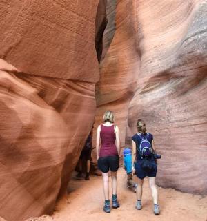 two people walking through a slot canyon