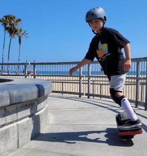 a young boy riding a skateboard down a sidewalk