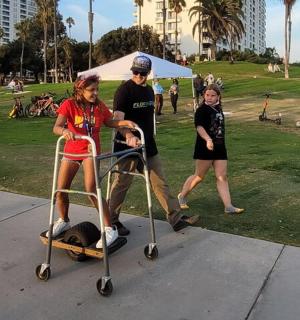 a man pushing a little girl on a scooter