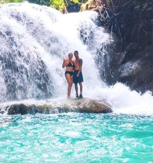 two people standing on a rock in front of a waterfall