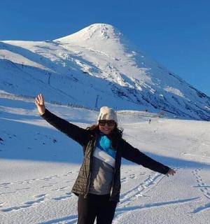 一位女士站在山前的雪地里