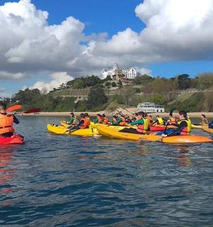 eine Gruppe von Menschen in Kajaks im Wasser