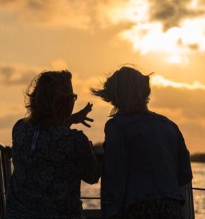 dvě ženy sedící na lodi a sledující západ slunce