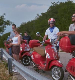 a group of people riding scooters on a road