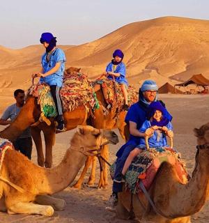 un gruppo di persone a cavallo di cammelli nel deserto