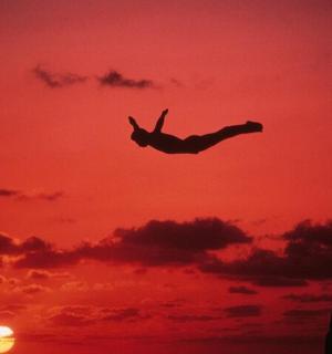 osoba letící na obloze při západu slunce