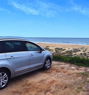 一辆银色的汽车停在海边的沙滩上