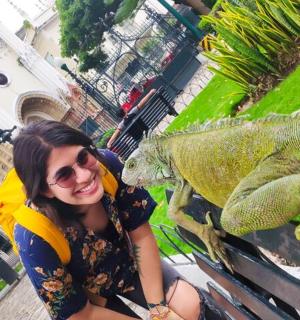 a woman sitting on a bench next to a iguana