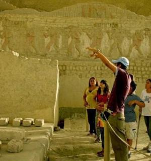 skupina lidí stojících před kamennou zdí