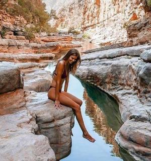 a woman sitting on a rock in the water