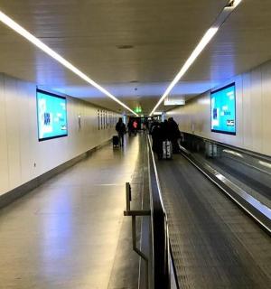 a hallway of an airport with people walking down a bowling alley