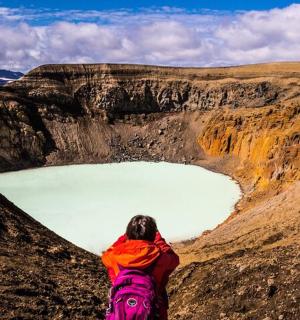 a person standing on a mountain looking at a lake