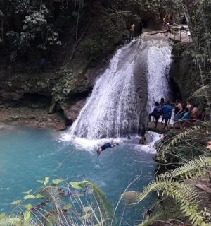 a person is jumping into a pool in front of a waterfall