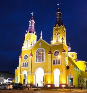 a yellow church with a clock tower at night