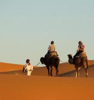 three people riding on horses in the desert