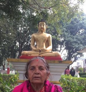 an older woman standing in front of a statue