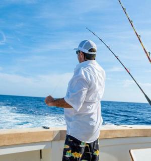 a man standing on a boat holding a fishing rod