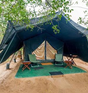 a tent with chairs and a table in the dirt