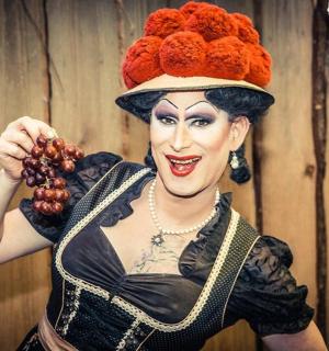一名手持一串葡萄、扮成小丑的女子