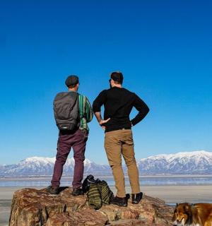 two men standing on top of a rock with a dog
