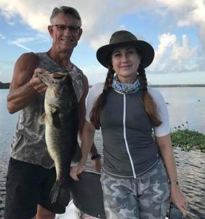 a man and a woman holding a fish in a lake
