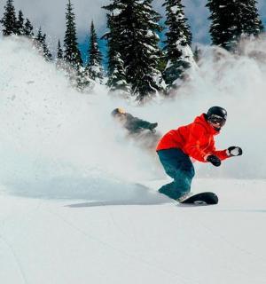 a man riding a snowboard down a snow covered slope