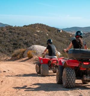 a group of people riding atvs on a dirt road
