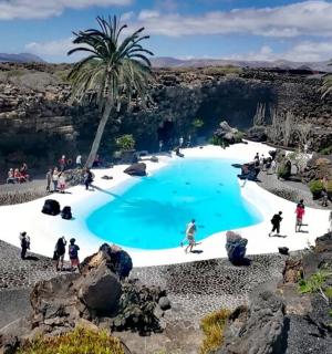 a group of people standing around a swimming pool in a canyon