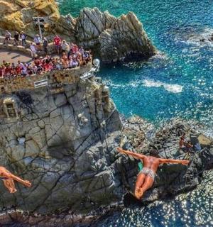 dva lidé skákající z útesu do oceánu