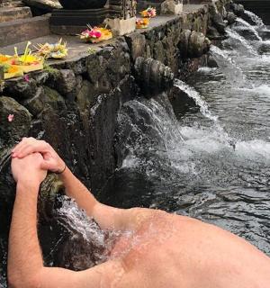 muž ve vodě před vodopádem