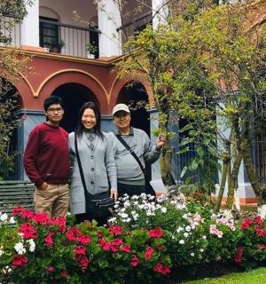 三个人站在一栋有花的房子前