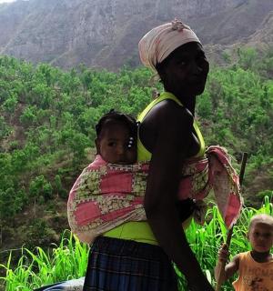 a woman holding a baby in her back